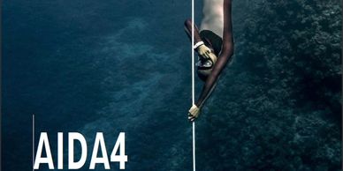 Freediver descending underwater with AIDA4 logo.