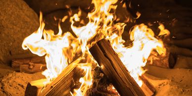 A close-up view of a bright, crackling campfire with wooden logs.