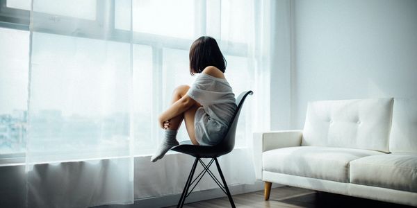 Girl sitting in a chair looking out the window. 