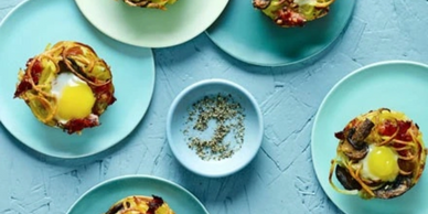 Egg nests with mushrooms and crispy bacon on blue plates.