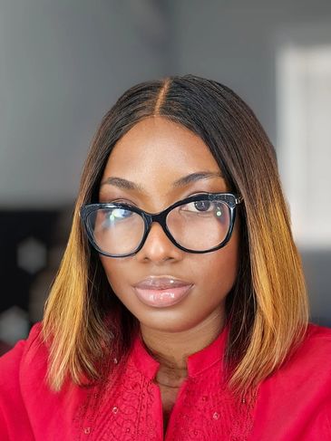 Woman with shoulder-length ombre hair and black glasses wearing a red top.