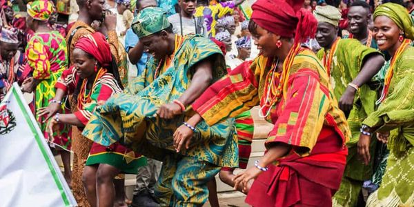 People in colorful traditional attire dancing joyfully at a cultural event.