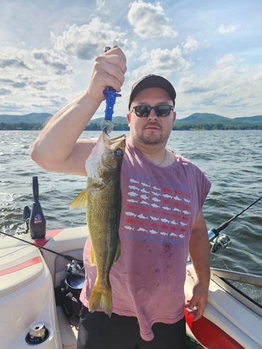 Man on boat holding a large fish he caught while fishing.