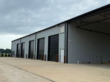 Exterior of a large industrial warehouse with multiple closed garage doors.