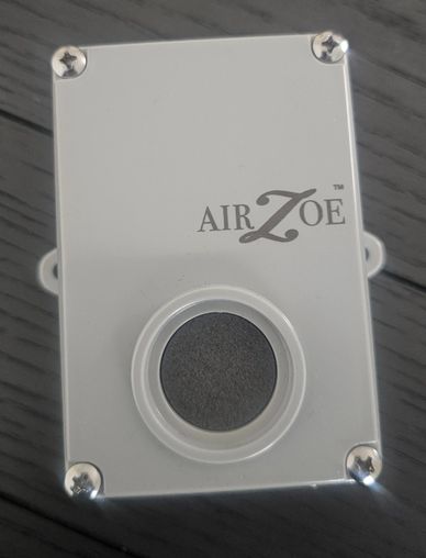 White Air Zoe device with a circular sensor on a wooden surface.
