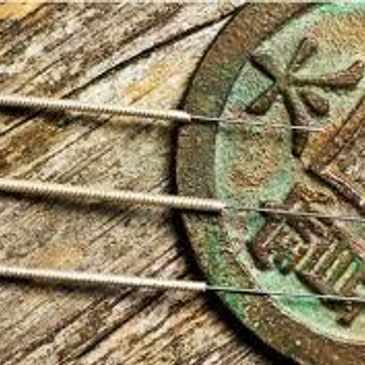 Ancient Chinese Coin with Acupuncture needles laying across it.