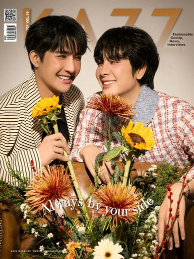 Two smiling men holding sunflowers surrounded by vibrant flowers on a magazine cover.