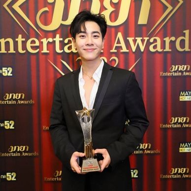 Man in black suit holding an award at an entertainment event.