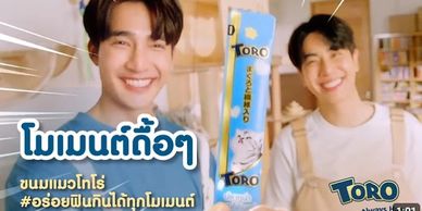 Two smiling men holding Toro snack in a cheerful setting.