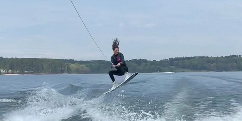 wakeboard jumping over wake behind ski boat on Lake James 