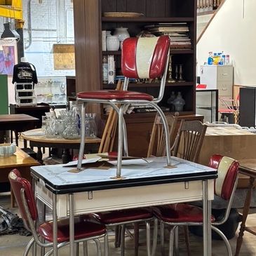 Antiqeue booth with table and set of 4 vintage red vinyl chairs. 