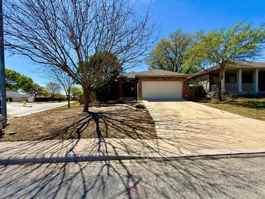 House with two trees and on a driveway.