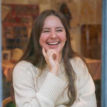Smiling woman sitting at a table indoors.