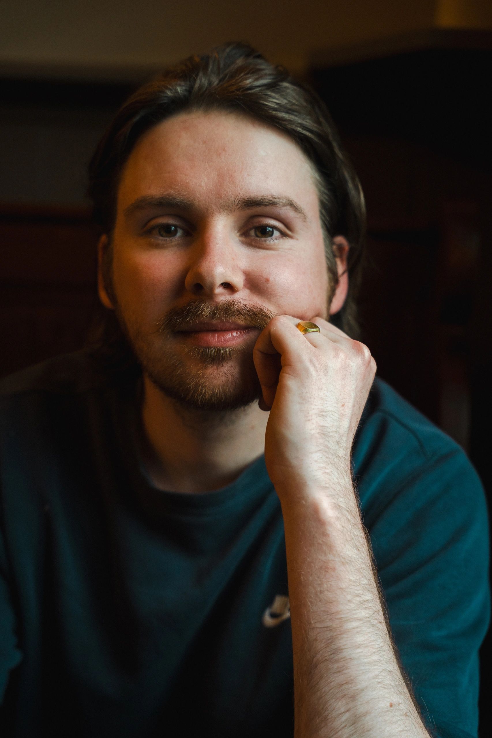 Young man with a beard resting his chin on his hand.