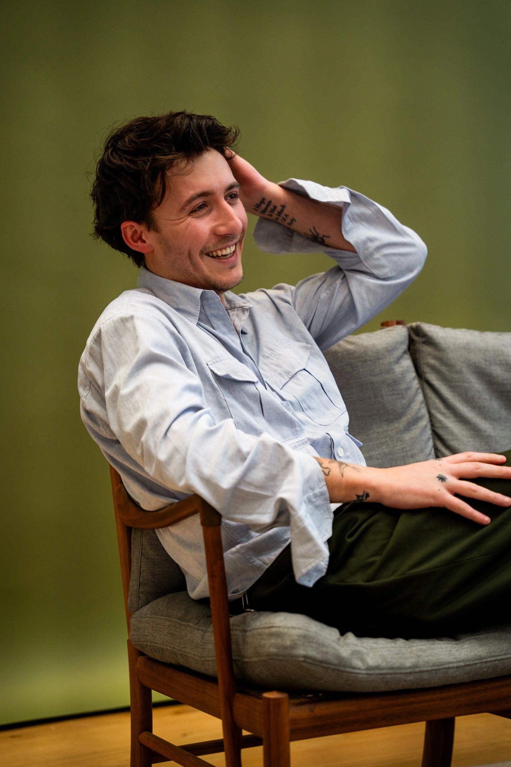 A man laughing while sitting on a wooden chair.
