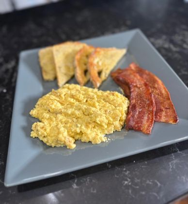 Scrambled eggs, bacon, and toast breakfast.