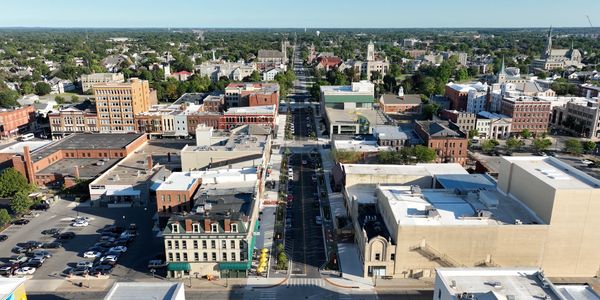 Aerial view of a small city with a central street and historic buildings.