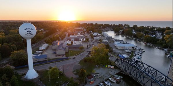Sunset over Vermilion town with water tower, bridge, and marina.