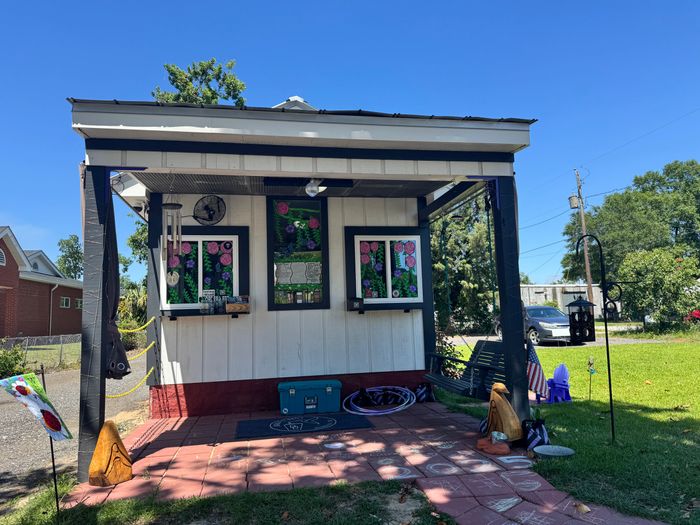 Small outdoor cafe with decorated windows and a garden swing under a clear blue sky.