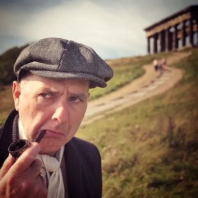 Man in vintage attire smoking a pipe near a historic temple.