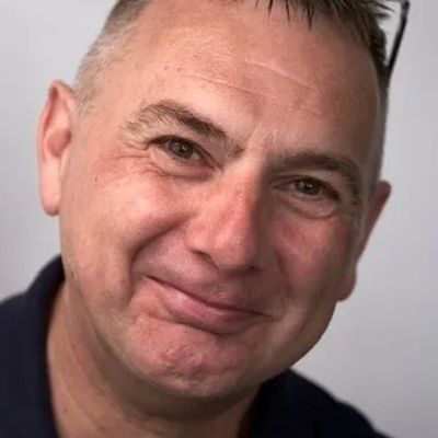 Smiling middle-aged man with short hair and light wrinkles.