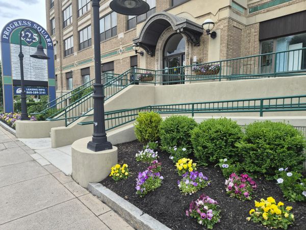 Entrance to Progress Square with colorful flower beds and a large sign.