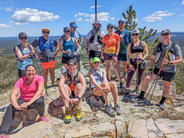 Group of hikers posing on a rocky summit under a blue sky.