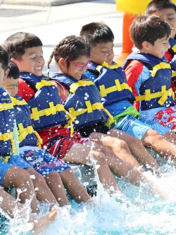 Children in life jackets splashing water.