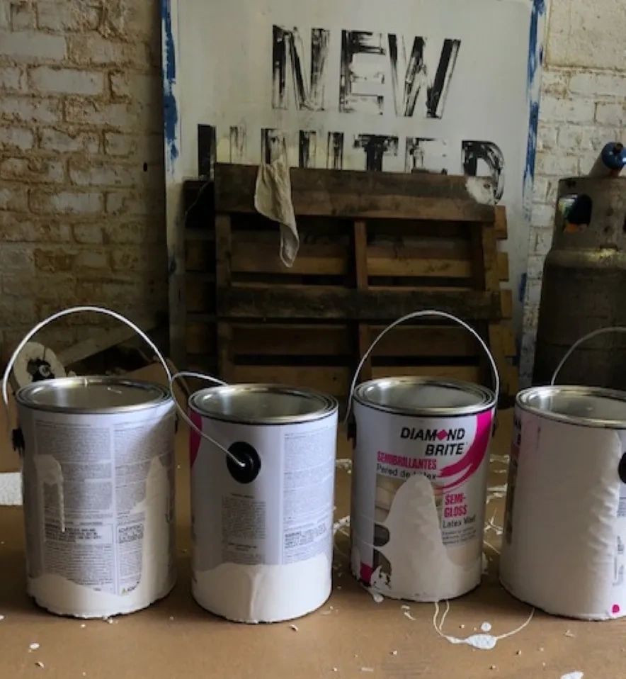 Rustic picture of Paint Cans and an old New United Sign.
