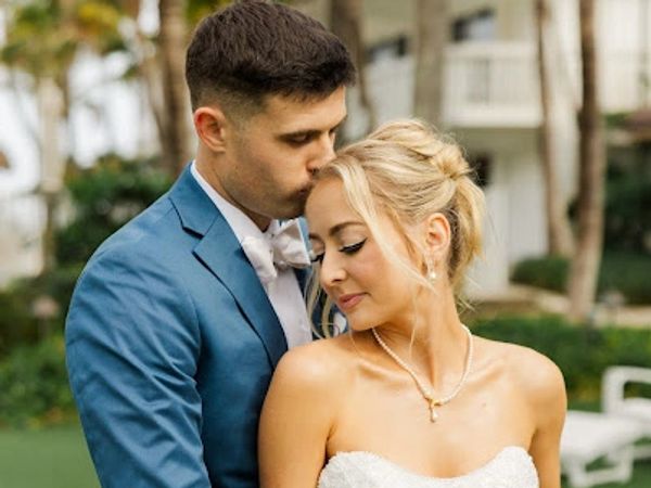 Groom kissing bride's forehead in a tender moment.