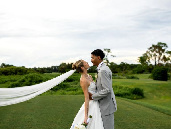 Bride and groom share a joyful moment outdoors.