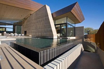 Modern house with an infinity pool under a clear blue sky.