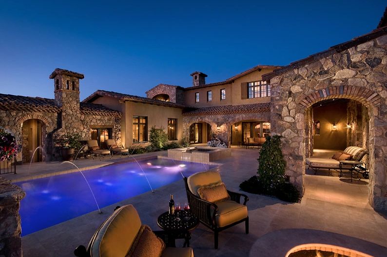 Elegant outdoor pool area with stone walls and cozy seating at dusk.