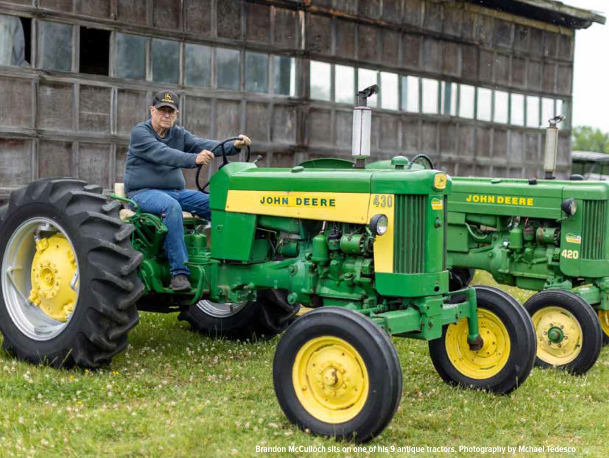 Man sitting on a vintage John Deere tractor.