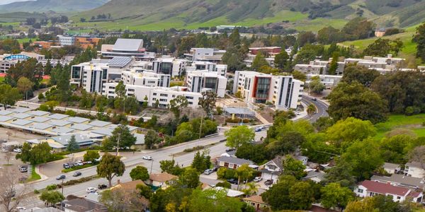 A suburban neighborhood with modern buildings and green hills in the background.