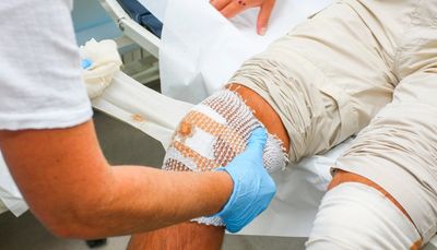 Health care provider dressing a patient's leg wound with a bandage during wound care treatment