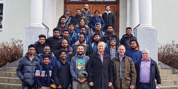 Group photo of diverse people standing on steps outside a building.