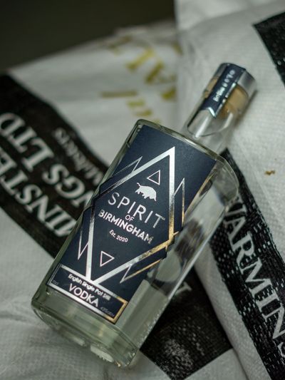 Bottle of Spirit of Birmingham Vodka lying on a bag of English heritage grain
