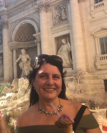 Woman enjoying ice cream in front of a historic fountain with statues.