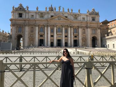 Woman posing in front of St. Peter's Basilica in Vatican City on a sunny day.