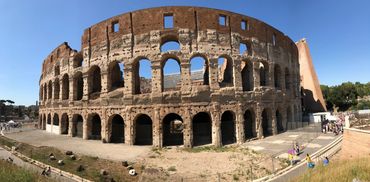 Panoramic view of the ancient Roman Colosseum under a clear blue sky.