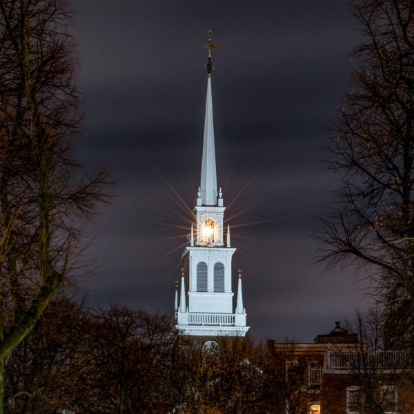 Illuminated church steeple at night with glowing clock.