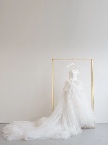 Elegant white wedding dress with a long train on a gold rack.