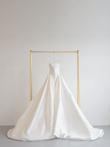 Elegant white strapless wedding dress on a gold rack.