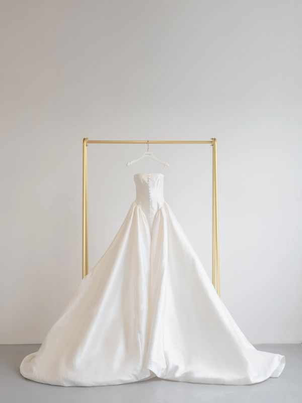 Elegant white strapless wedding gown displayed on a gold rack.