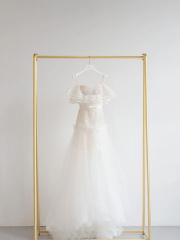 Elegant white wedding dress hanging on a gold rack.