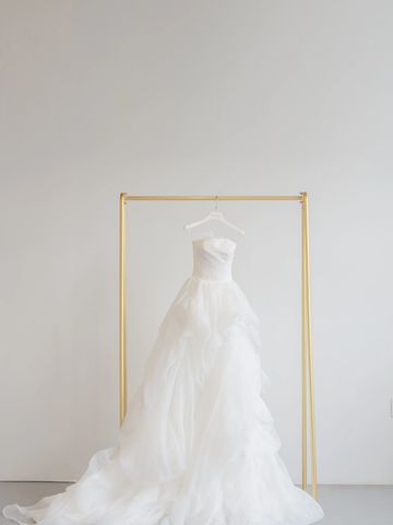 Elegant white wedding dress hanging on a gold rack.
