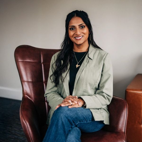 Woman sitting on a brown leather chair, smiling.