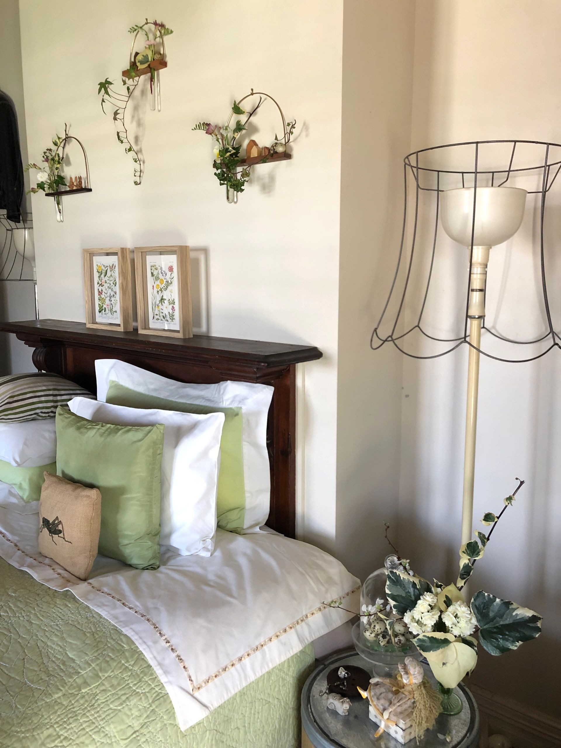Bed with green pillows and floral wall decorations.