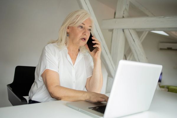 Concerned woman listening on the phone with a pc.